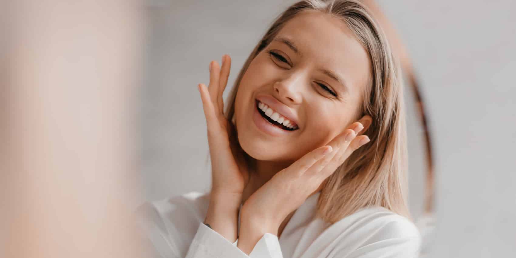 woman smiling holding face - Highlands Periodontics and Implant Dentistry